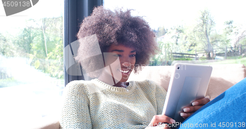 Image of african american woman at home using digital tablet