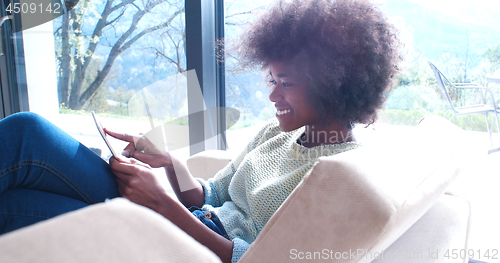 Image of african american woman at home using digital tablet