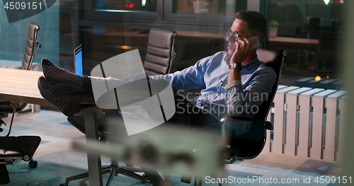 Image of businessman sitting with legs on desk at office