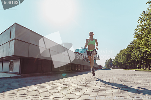 Image of Pretty sporty woman jogging at city