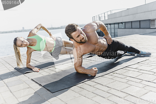 Image of Fit fitness woman and man doing fitness exercises outdoors at city