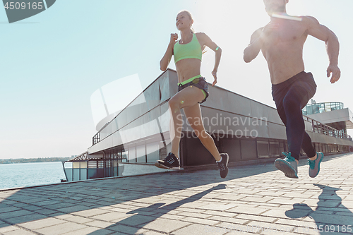 Image of Pretty sporty woman and man jogging at city