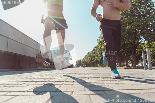 Image of Pretty sporty woman and man jogging at city