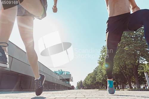 Image of Pretty sporty woman and man jogging at city