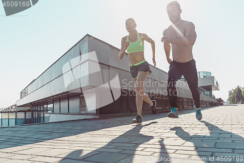 Image of Pretty sporty woman and man jogging at city