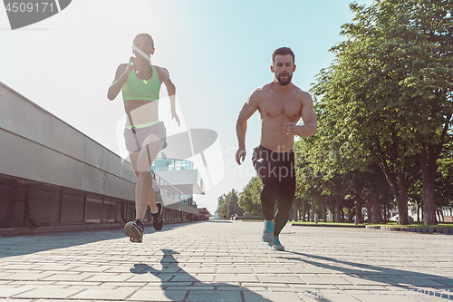 Image of Pretty sporty woman and man jogging at city