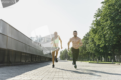 Image of Pretty sporty woman and man jogging at city