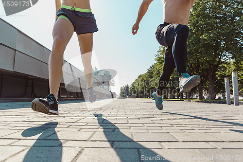 Image of Pretty sporty woman and man jogging at city