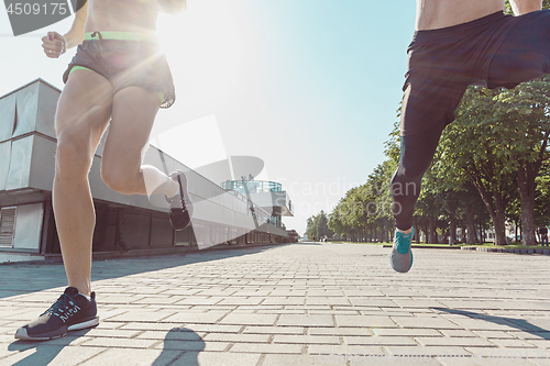 Image of Pretty sporty woman and man jogging at city