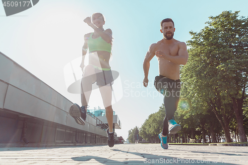 Image of Pretty sporty woman and man jogging at city