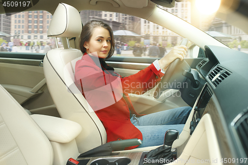 Image of Driving around city. Young attractive woman driving a car