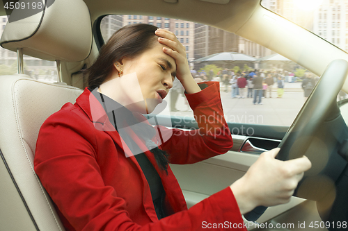 Image of Driving around city. Young attractive woman driving a car