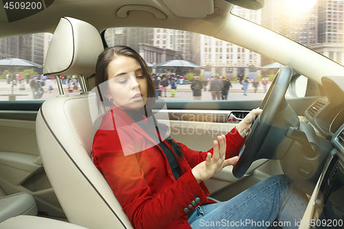 Image of Driving around city. Young attractive woman driving a car