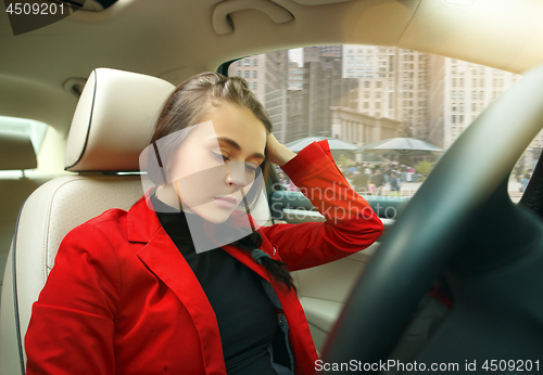 Image of Driving around city. Young attractive woman driving a car