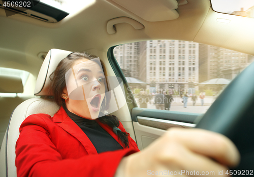 Image of Driving around city. Young attractive woman driving a car