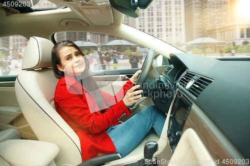 Image of Driving around city. Young attractive woman driving a car