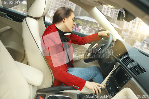 Image of Driving around city. Young attractive woman driving a car