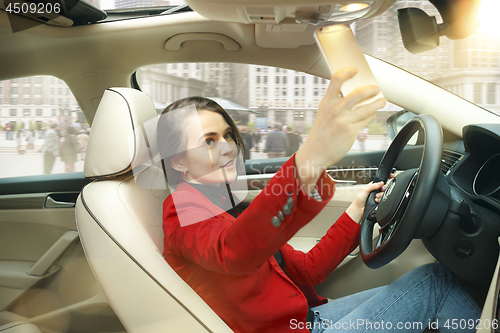 Image of Driving around city. Young attractive woman driving a car