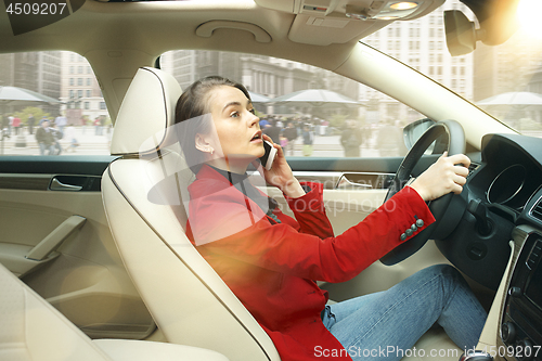 Image of Driving around city. Young attractive woman driving a car