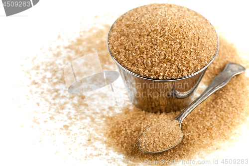 Image of Brown cane sugar in metal bowl and spoon isolated on white backg