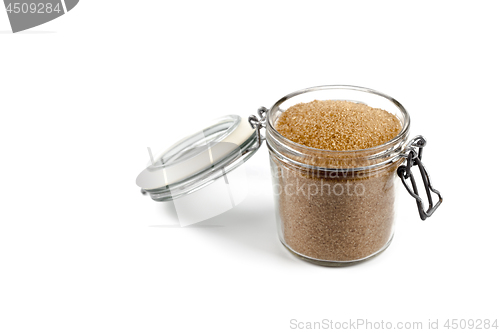 Image of Brown cane sugar in glass jar isolated on white background.