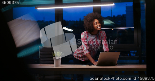 Image of black businesswoman using a laptop in night startup office