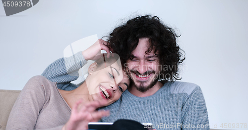 Image of couple relaxing at  home with tablet computers