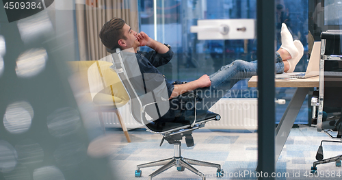 Image of businessman sitting with legs on desk