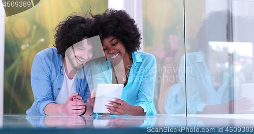 Image of Couple relaxing together at home with tablet computer