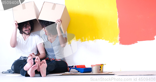 Image of young multiethnic couple playing with cardboard boxes