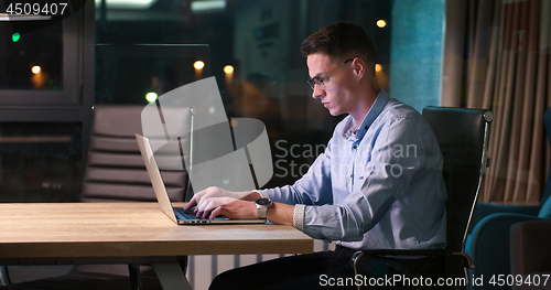 Image of man working on laptop in dark office