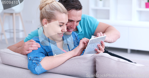 Image of couple relaxing at  home with tablet computers