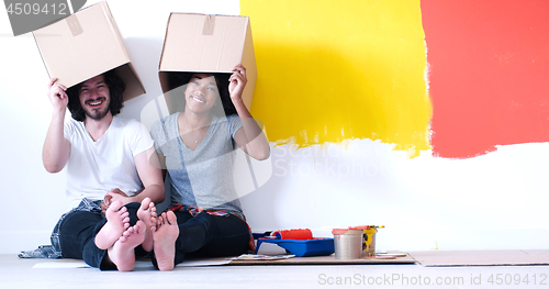 Image of young multiethnic couple playing with cardboard boxes