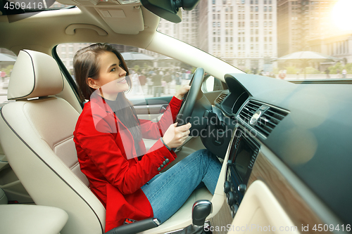 Image of Driving around city. Young attractive woman driving a car