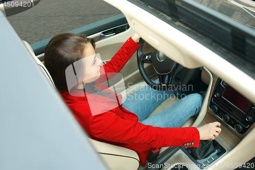 Image of Driving around city. Young attractive woman driving a car