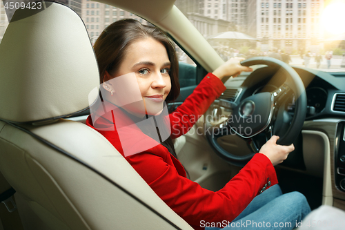 Image of Driving around city. Young attractive woman driving a car