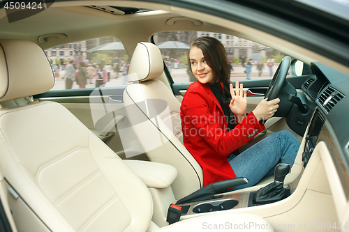 Image of Driving around city. Young attractive woman driving a car