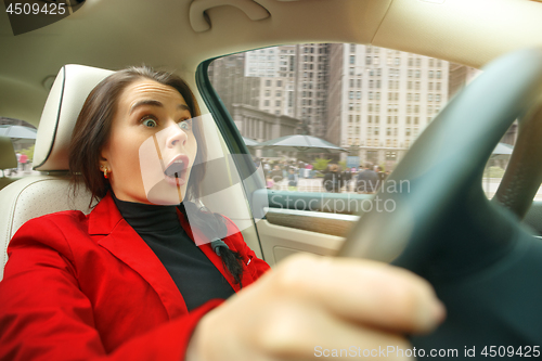 Image of Driving around city. Young attractive woman driving a car