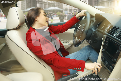 Image of Driving around city. Young attractive woman driving a car