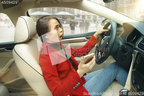 Image of Driving around city. Young attractive woman driving a car