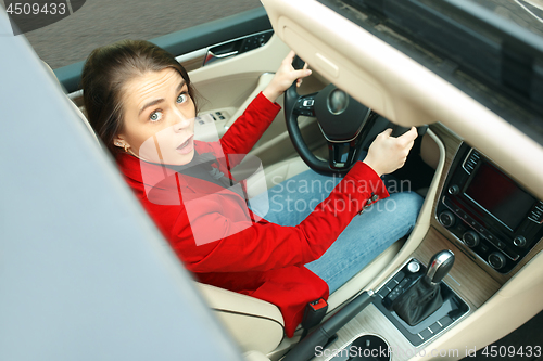 Image of Driving around city. Young attractive woman driving a car