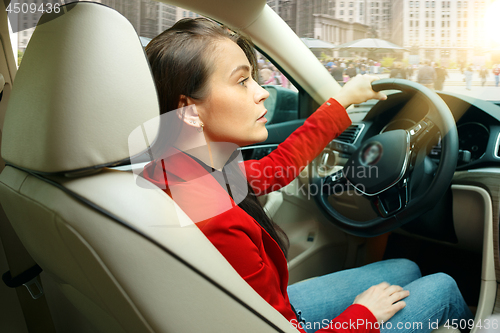 Image of Driving around city. Young attractive woman driving a car