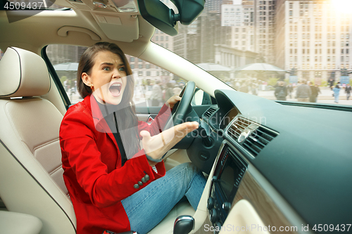 Image of Driving around city. Young attractive woman driving a car