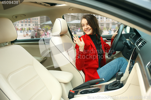 Image of Driving around city. Young attractive woman driving a car