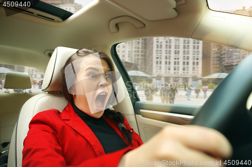 Image of Driving around city. Young attractive woman driving a car