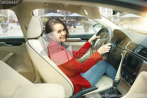 Image of Driving around city. Young attractive woman driving a car