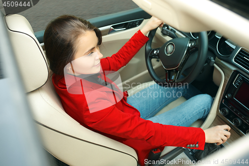 Image of Driving around city. Young attractive woman driving a car