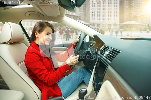 Image of Driving around city. Young attractive woman driving a car