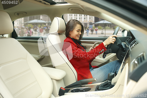 Image of Driving around city. Young attractive woman driving a car