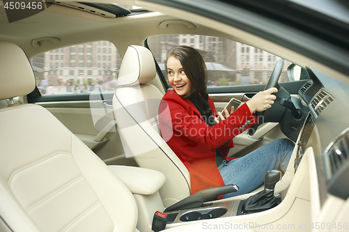 Image of Driving around city. Young attractive woman driving a car